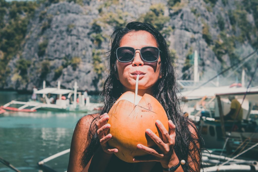 Frau trinkt aus einer Frucht im Urlaub